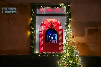 Julpyntat skyltfönster bredvid julgran med julkulor